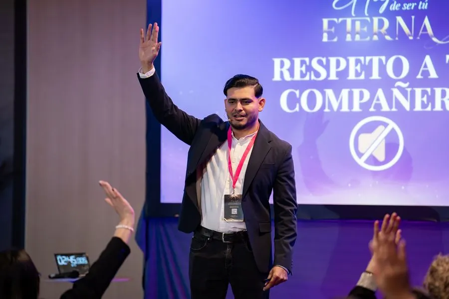 Engels Arce dirigiéndose a la sala desde el escenario con la mano en alto