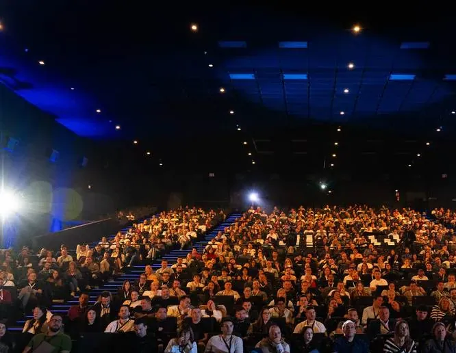Auditorio completo con cientos de asistentes sentados mirando al escenario