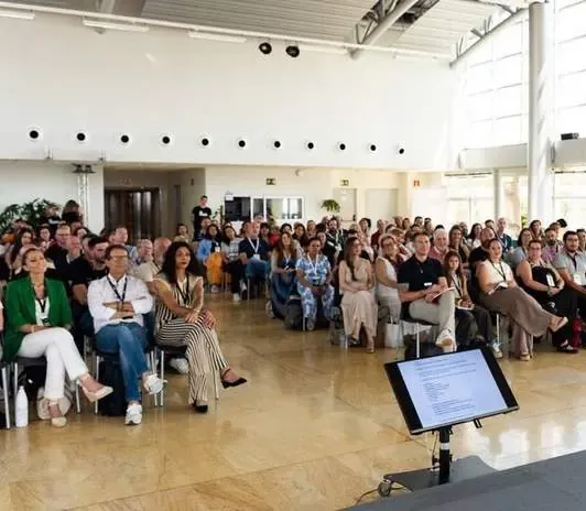 Sala luminosa con público sentado atendiendo a una charla