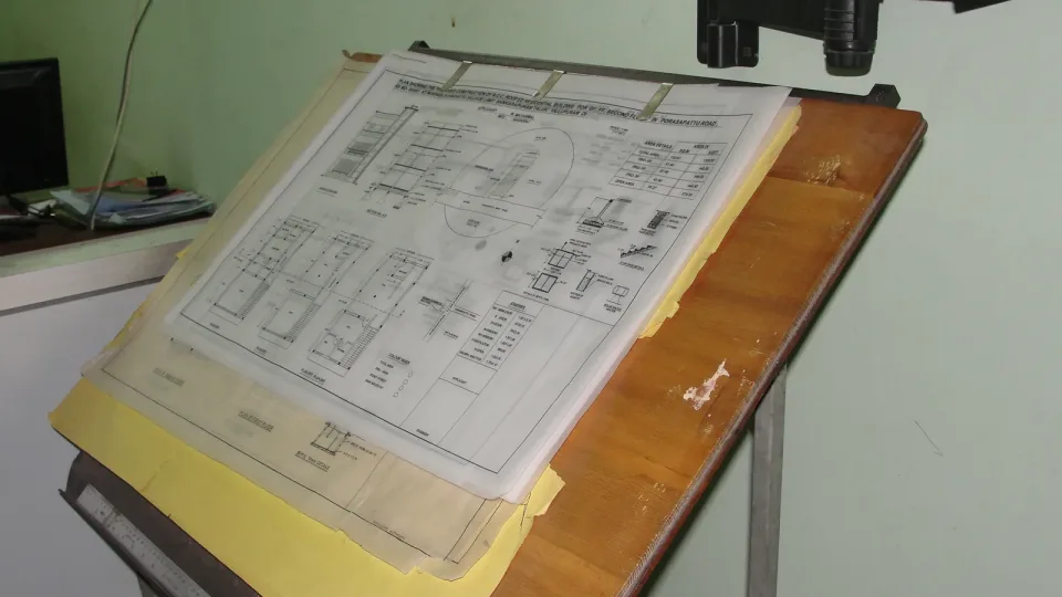 Fotografía de archivo: tablero de dibujo inclinado con un plano técnico sujeto con cinta